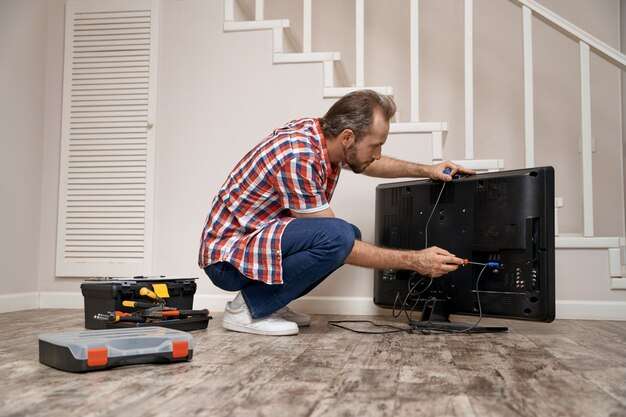 young caucasian service man fixing tv set 386185 3098 Home Solution India